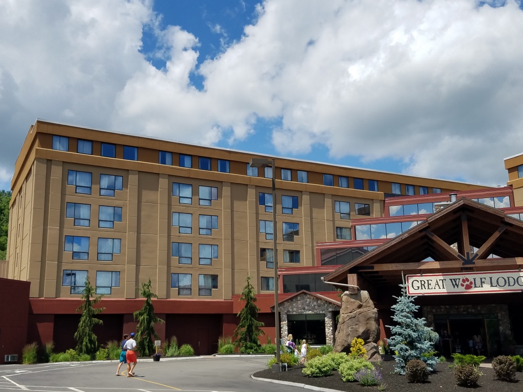 Great Wolf Lodge hotel exterior with rustic wooden entrance, stone accents, and modern multi-story building under cloudy sky