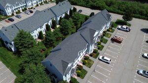 Aerial view of modern townhouse complex with gray roofs, white siding, and organized parking lot with numbered spaces