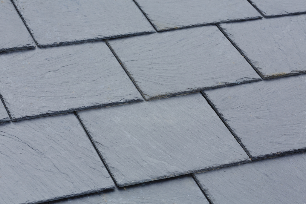 Close-up view of gray slate roof tiles arranged in overlapping rows, showing natural stone texture and weathered edges