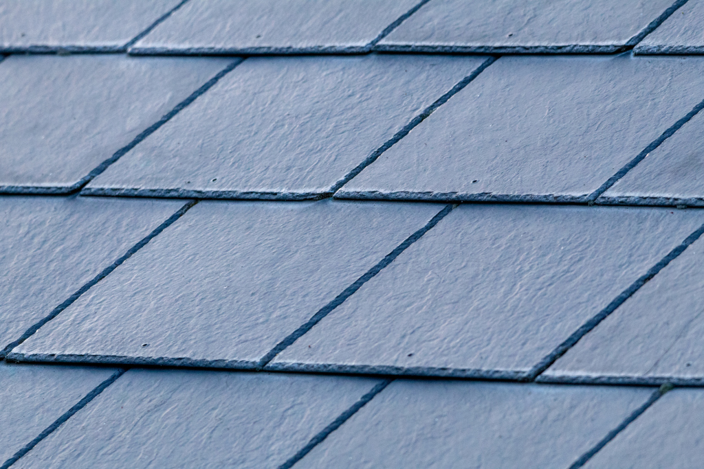 Close-up view of gray slate roof shingles arranged in overlapping rows, showing natural stone texture and weathered surface details