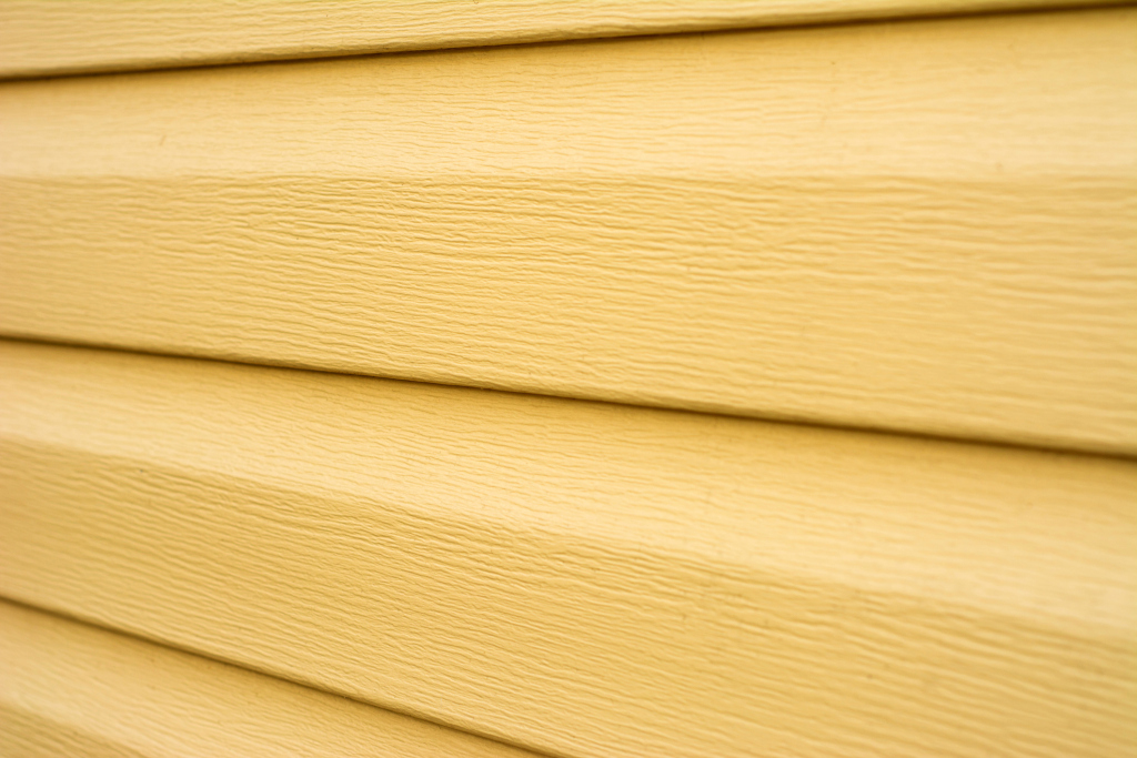 Close-up view of light wood grain siding panels with horizontal lines and natural texture pattern