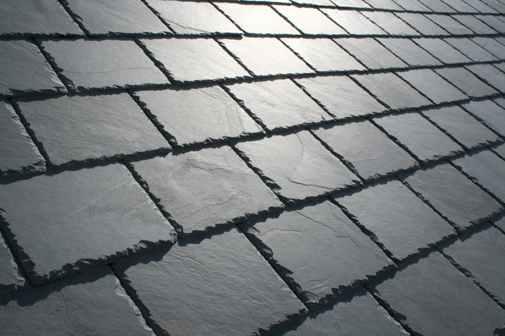 Close-up view of weathered slate roof tiles with rough edges and natural gray coloring arranged in overlapping rows