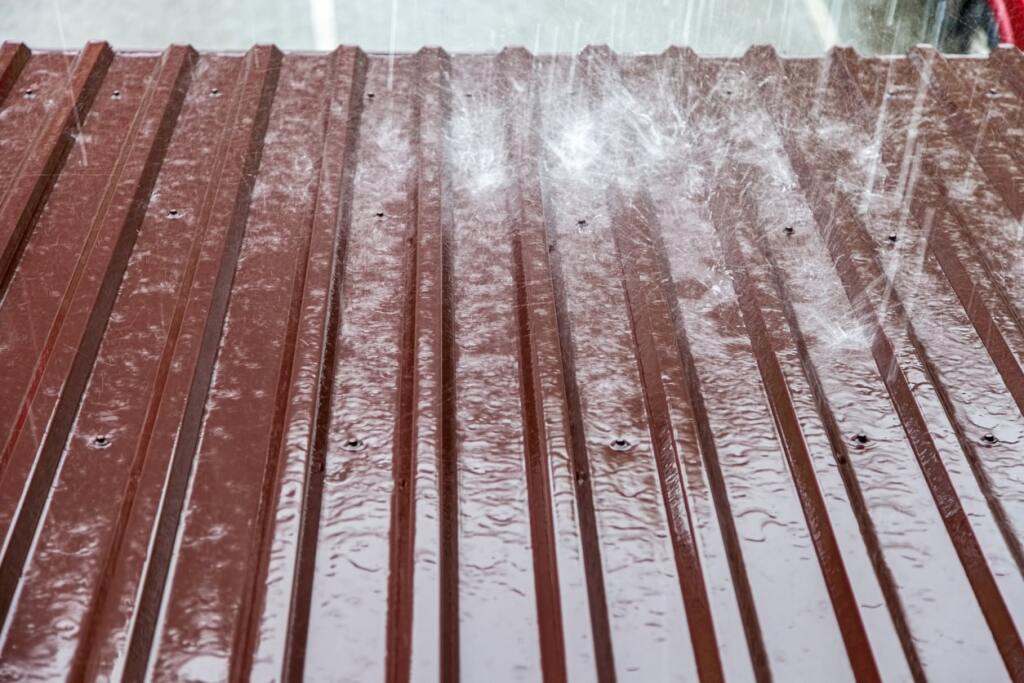 Rain falling on wet wooden deck with parallel planks and visible screws, creating water droplets and puddles on brown wood surface
