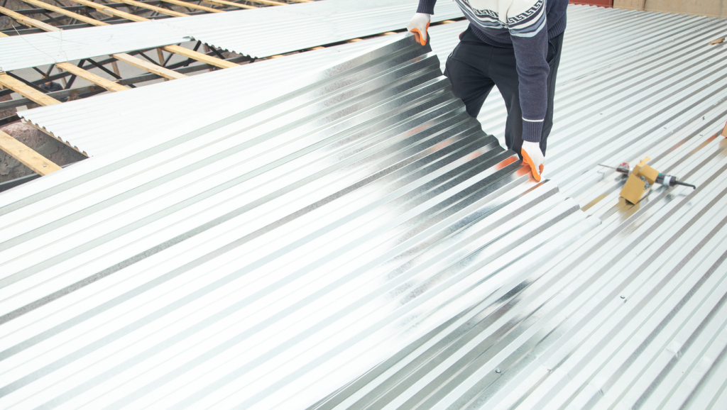 Construction worker installing corrugated metal roofing sheets on wooden frame structure during building construction project