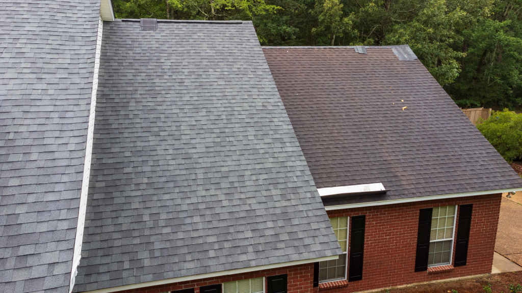 Aerial view of residential homes with gray and brown asphalt shingle roofs surrounded by lush green trees