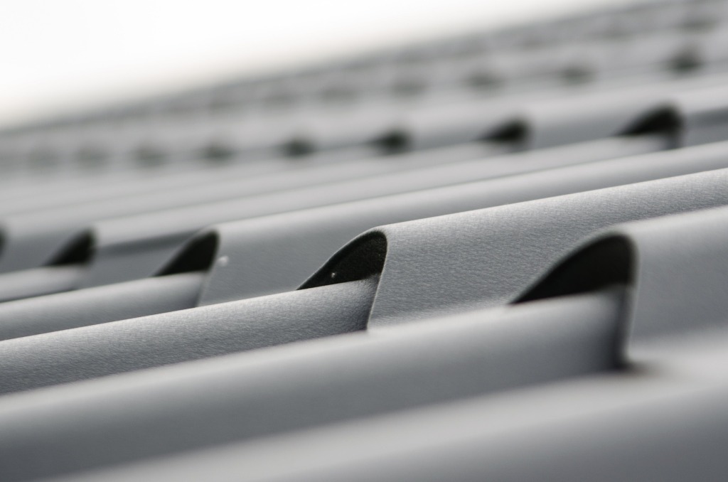 Close-up view of gray corrugated metal roofing sheets showing curved ridges and valleys with shallow depth of field